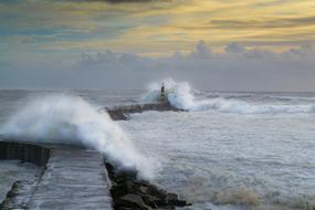 Landscape of the beach, with the lighthouse, among the sea, with waves, at beautiful and colorful sunset