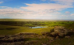 Beautiful landscape with the rocks and river, among the green fields and trees