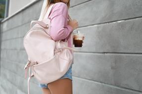 photo of a girl with a pink backpack and a drink in her hand close-up