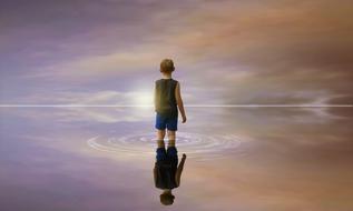 Child in the water with the reflection of the beautiful and colorful sky