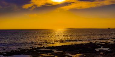 photo of an orange sky over a warm sea