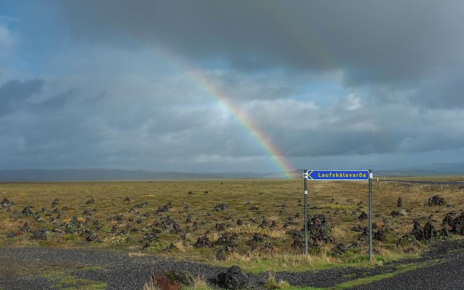rainbow at Dark Cloudy Sky over rural landscape