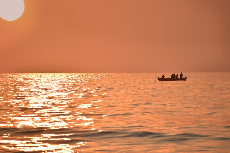 Silhouette of the boat with people, on the beautiful waterscape with ripple, in colorful sunrie