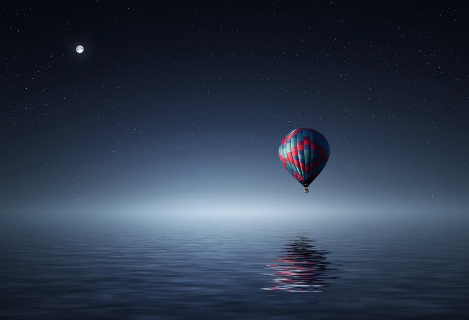 Colorful Hot Air Balloon above the lake with the light on horizon