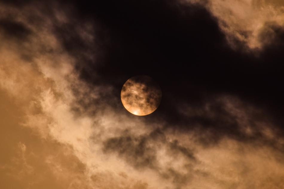 the moon in the sky behind the clouds at dusk