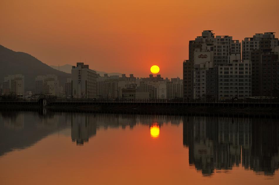 panorama of the city by the river against the background of orange dawn