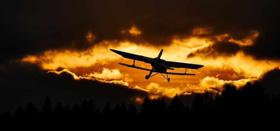 plane against the background of a fiery sky and black clouds