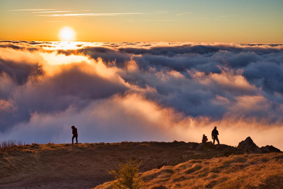 People on the beautiful and colorful mountain, among the clouds, at colorful sunset on background, in France