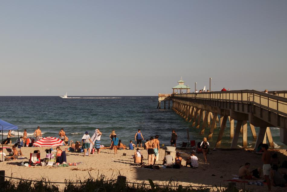 people relax on the beach near the pier in summer