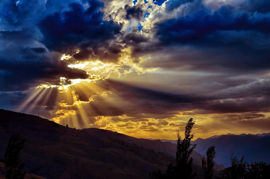 sunshine through storm clouds over mountains