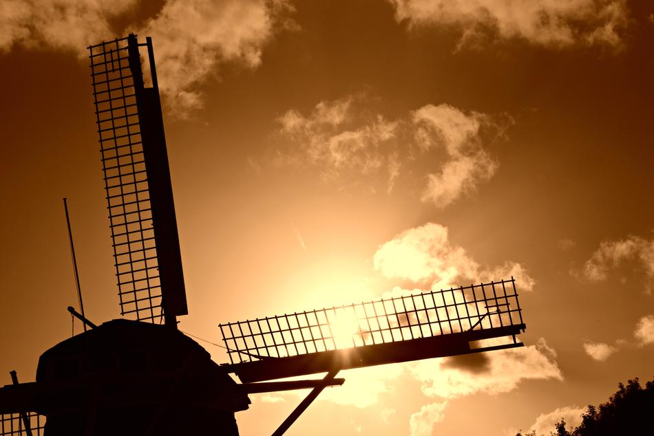 silhouette of a dutch windmill against a yellow sky