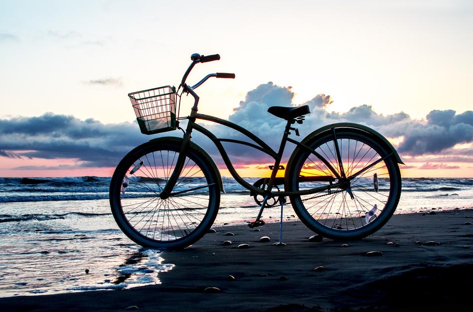 bike is parked on the beach by the sea in the evening