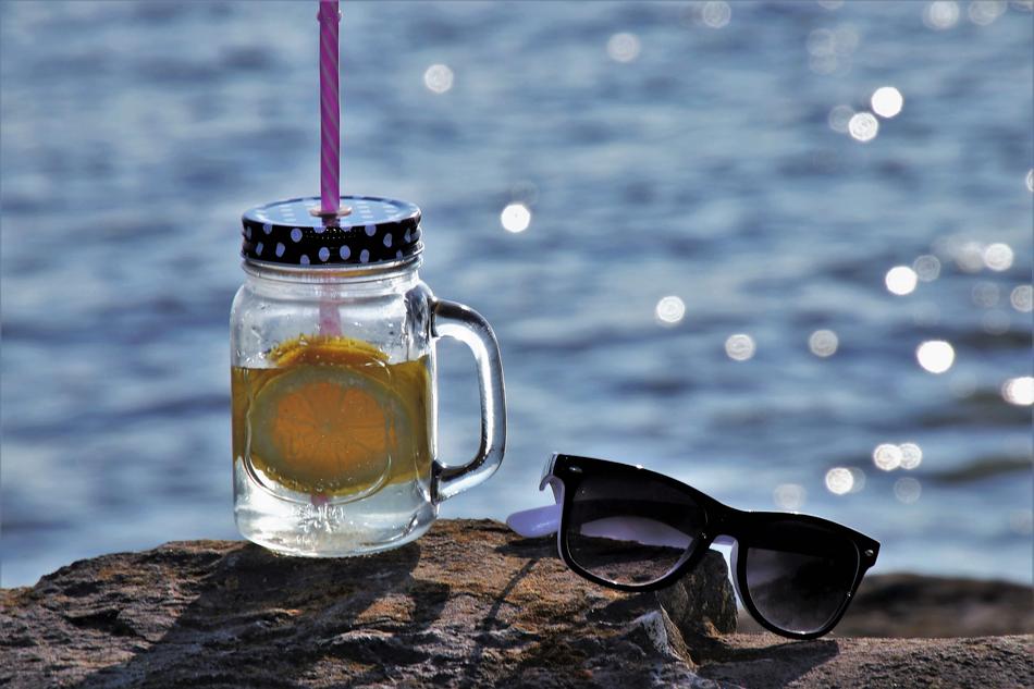 lemonade and sunglasses on a stone against the sea