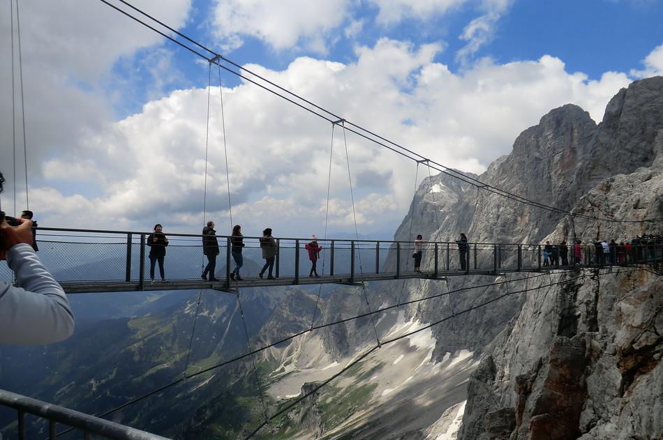 People, on the Dachstein-Hängebrücke, among the beautiful Dachstein in Austria, under the blue sky with clouds