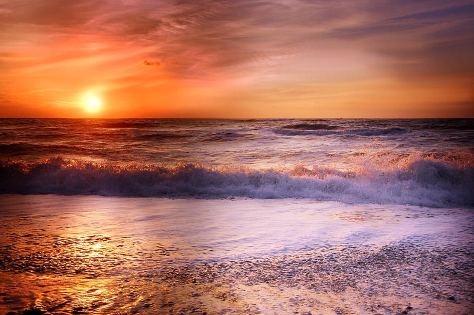 sea surf in the rays of the sunset in summer