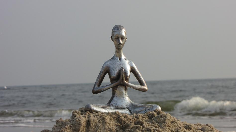 meditation, silver female sculpture on rock at Sea