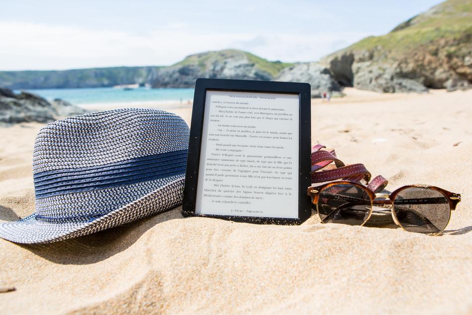 hat, sunglasses and e-book on the beach