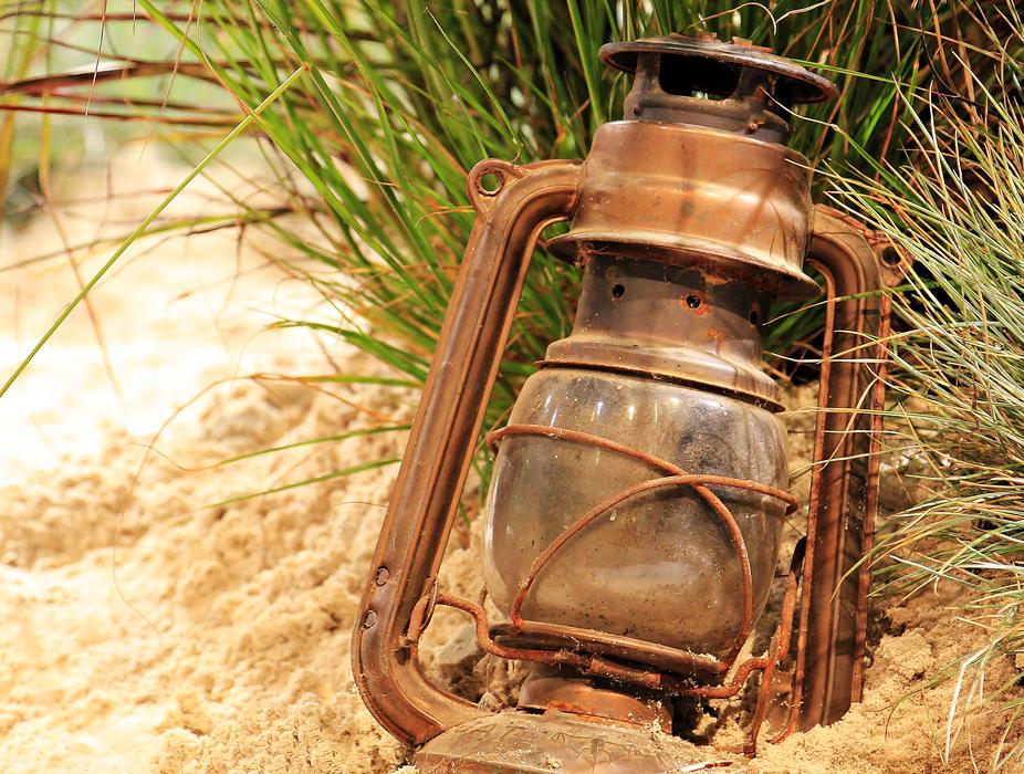 old rust Lantern in the sand on the beach close up