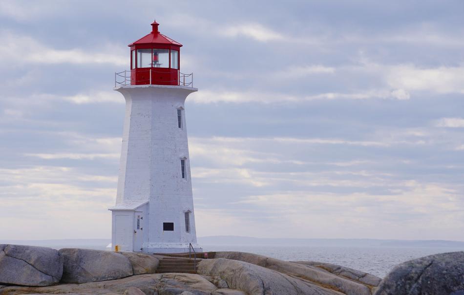 photo of a red and white lighthouse on the ocean in Canada