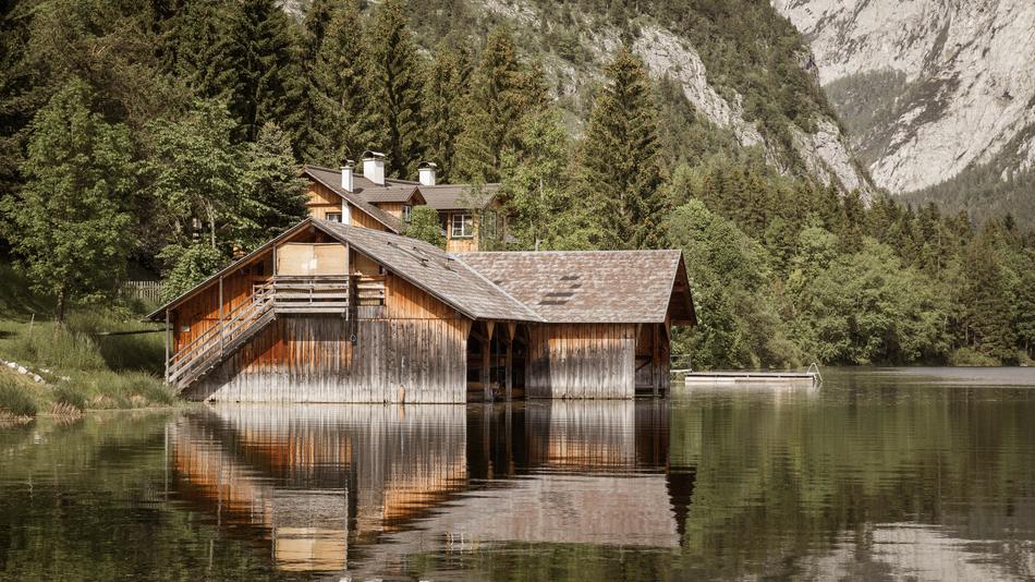 Beautiful landscape with the wooden house on the shore, among the green trees, among the beautiful Dolomites, Italy