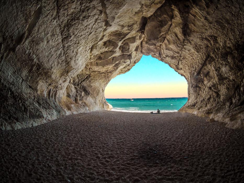 Beautiful landscape with the view of the turquoise water, at colorful sunset, from the rocky tunnel