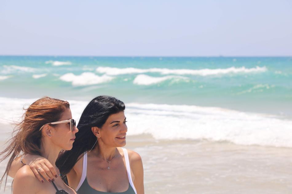 two girls on the beach look at the horizon