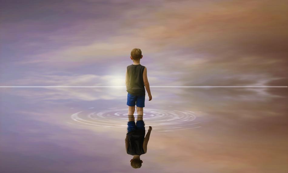 Child in the water with the reflection of the beautiful and colorful sky