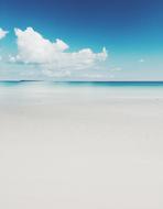 white sand on the beach, blue sky and clouds