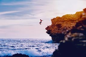 man jumping from cliff to ocean, usa, california