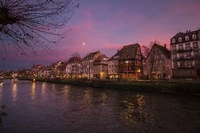 Beautiful and colorful landscape of the river, with the houses and lights, on the shore, in France, at beautiful and colorful sunset