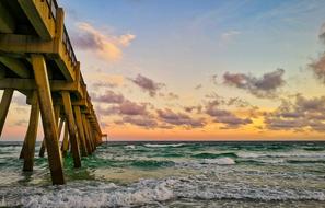 sunset over the waves under the pier