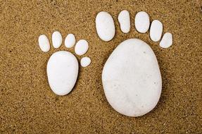 Beautiful, big and small feet, made of the stones, in the sand