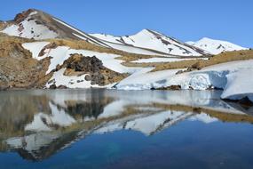 mountains are reflected in water in new zealand