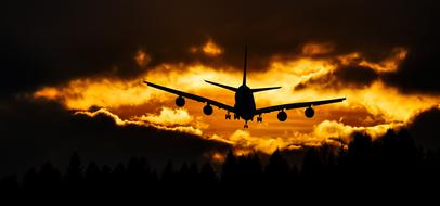 photo of a flying plane against the background of a fiery sky