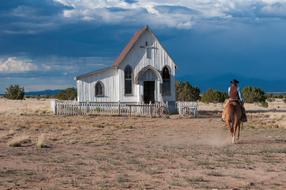 Beautiful landscape with the cowboy, near the white chapel, among the desert