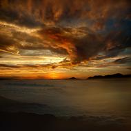 Beautiful landscape with the water and shore, at colorful sunset in the sky with clouds