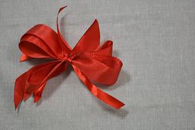 Close-up of the beautiful, shiny red Christmas bow, on the grey surface