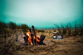 Camping with fire by the ocean at beautiful green and white sky on background