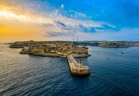 Beautiful coast of Valletta with the lighthouse in Malta at colorful sunrise