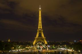 distant view of the eiffel tower in yellow night illumination