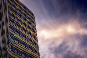 Shiny facade of the building with windows, at colorful and beautiful sunset with the clouds, in the evening