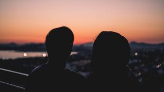 Back view with the silhouette of the couple, in the city, at beautiful and colorful sunset