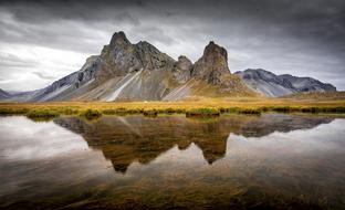 mountain peaks are reflected in a calm lake