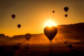 Beautiful hot air balloons fly over the mountains in Turkey on the background of golden, bright sunrise