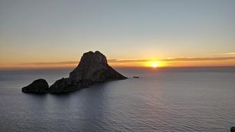 Beautiful waterscape with the Es Vedra in Ibiza, at beautiful and colorful sunset on horizon