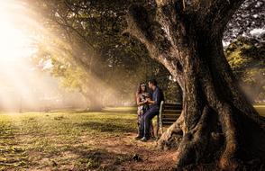 Couple, near the bench, among the beautiful and colorful plants, in sunlight