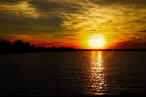 the setting sun on the horizon of the lake at dusk