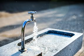 photo of a fountain with an open tap on the street