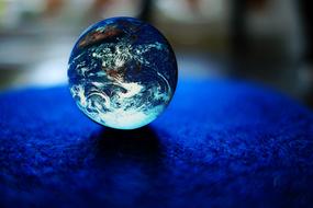 Close-up of the beautiful and colorful glass Earth globe, on the blue surface