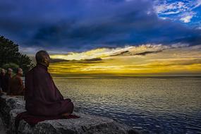 monk meditates on the lake at dusk
